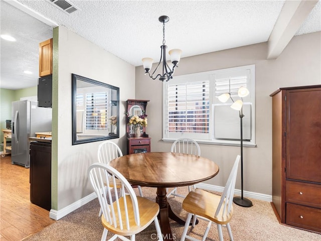 dining space featuring light hardwood / wood-style floors, a chandelier, and a textured ceiling