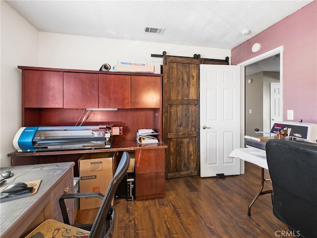 office area with dark hardwood / wood-style flooring, a barn door, and a textured ceiling