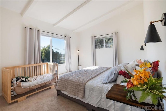 carpeted bedroom featuring lofted ceiling with beams and multiple windows