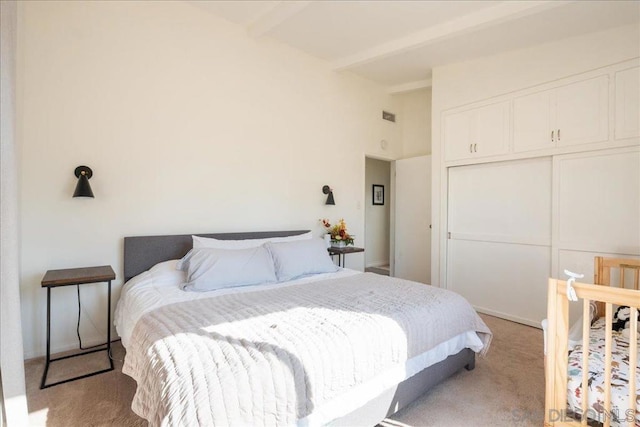 bedroom featuring light carpet, beam ceiling, and a closet