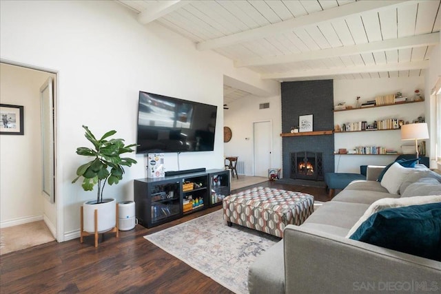 living room with dark hardwood / wood-style flooring, a brick fireplace, and vaulted ceiling with beams