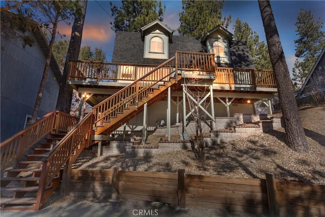 back house at dusk featuring a wooden deck