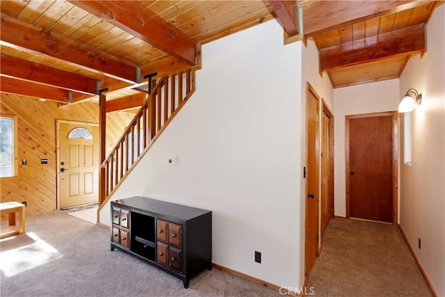 interior space with wood ceiling, light colored carpet, beamed ceiling, and wood walls