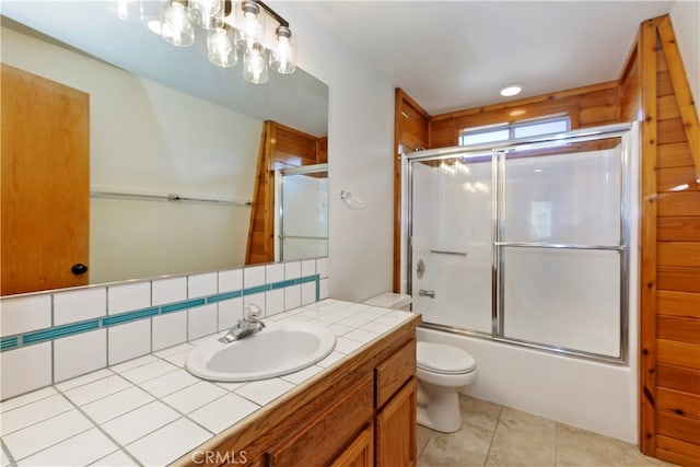 full bathroom featuring toilet, combined bath / shower with glass door, vanity, tile patterned flooring, and backsplash