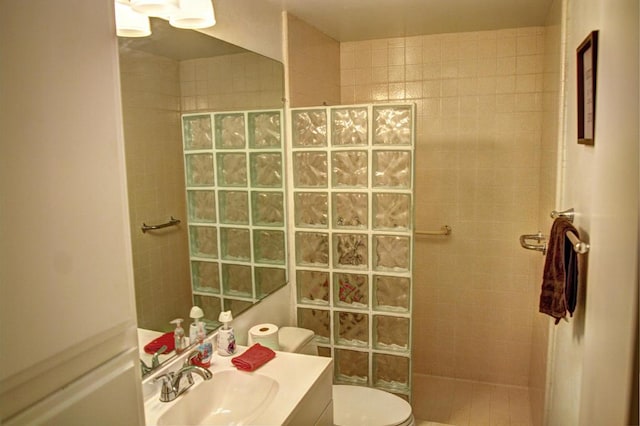 bathroom with vanity, toilet, and tiled shower