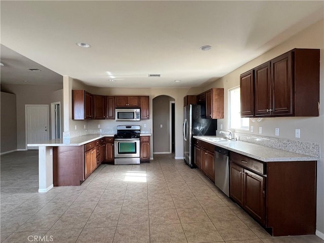 kitchen with sink, light tile patterned floors, appliances with stainless steel finishes, and kitchen peninsula