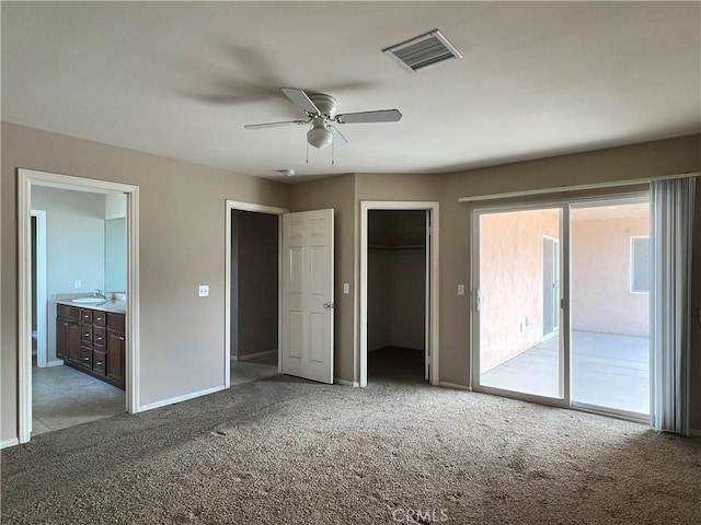 unfurnished bedroom featuring a walk in closet, access to exterior, a closet, ceiling fan, and ensuite bathroom