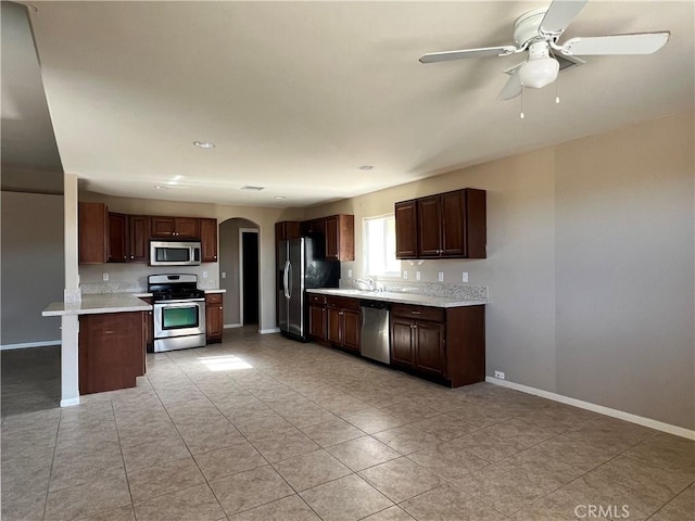 kitchen with ceiling fan, appliances with stainless steel finishes, sink, light tile patterned floors, and dark brown cabinetry