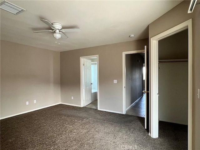 unfurnished bedroom featuring ceiling fan, a walk in closet, a closet, and ensuite bath