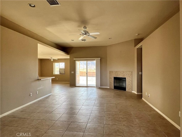 unfurnished living room featuring tile patterned flooring, ceiling fan, and a high end fireplace