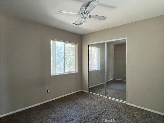 unfurnished bedroom with ceiling fan, a closet, and dark colored carpet