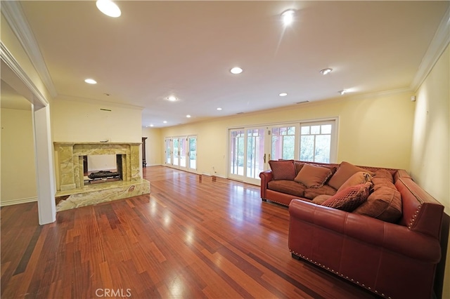 living room featuring a fireplace, wood-type flooring, ornamental molding, and french doors