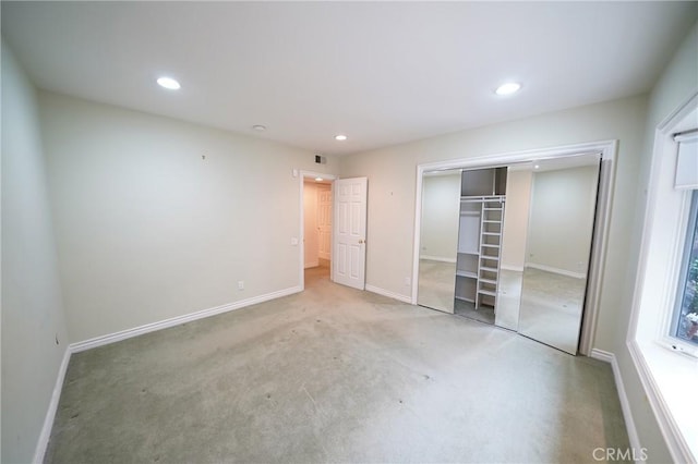 unfurnished bedroom with light colored carpet and a closet