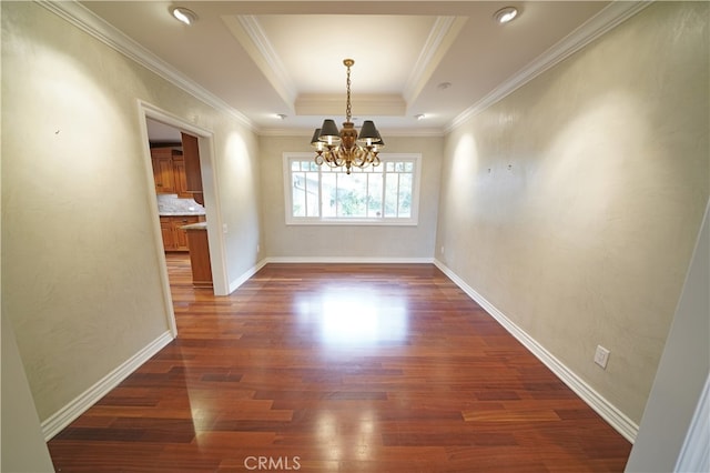 unfurnished dining area featuring a raised ceiling, ornamental molding, dark wood-type flooring, and an inviting chandelier