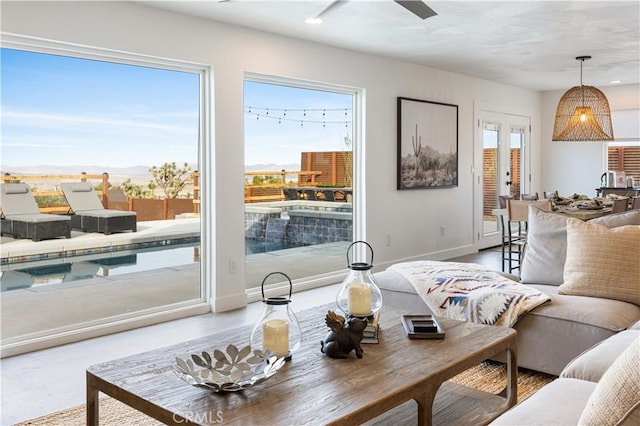 living room with ceiling fan, plenty of natural light, a mountain view, and french doors