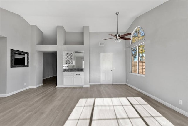 unfurnished living room with light hardwood / wood-style floors, vaulted ceiling, and ceiling fan