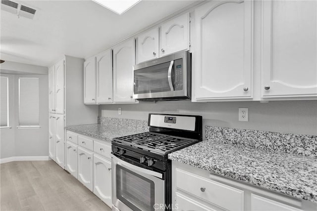 kitchen featuring light hardwood / wood-style floors, white cabinetry, light stone countertops, and stainless steel appliances