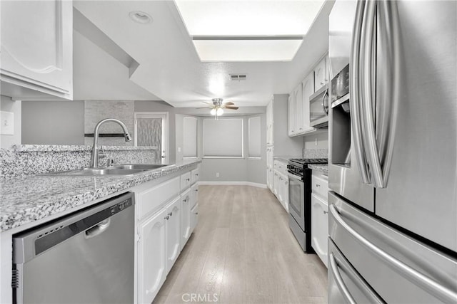 kitchen with sink, white cabinetry, light hardwood / wood-style flooring, and appliances with stainless steel finishes