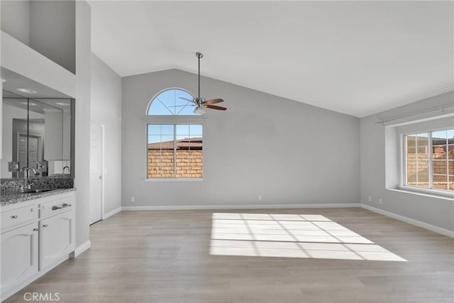 unfurnished living room featuring sink, ceiling fan, lofted ceiling, and a wealth of natural light