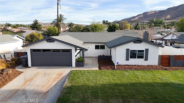 ranch-style home with a garage, a mountain view, and a front yard