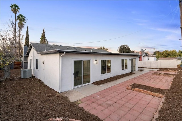 back house at dusk featuring a patio and cooling unit