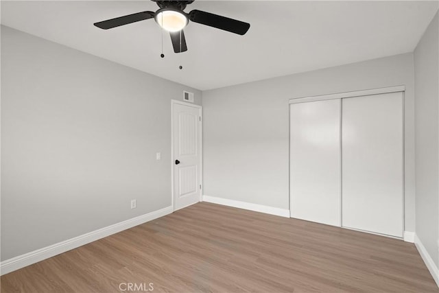 unfurnished bedroom featuring wood-type flooring, ceiling fan, and a closet