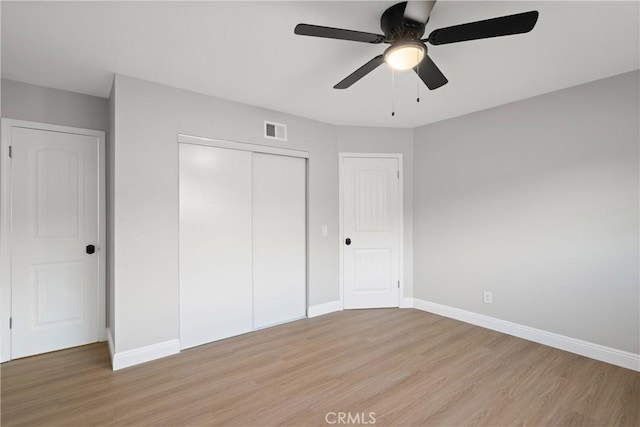 unfurnished bedroom featuring light hardwood / wood-style floors, a closet, and ceiling fan