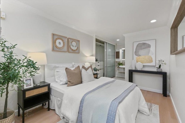 bedroom with ensuite bath, ornamental molding, and light hardwood / wood-style flooring