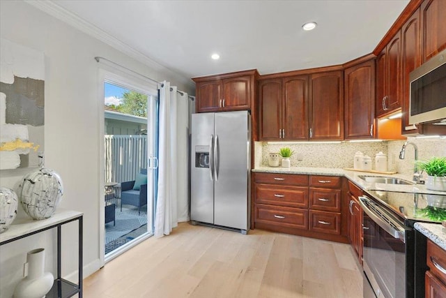 kitchen featuring appliances with stainless steel finishes, sink, backsplash, ornamental molding, and light hardwood / wood-style flooring