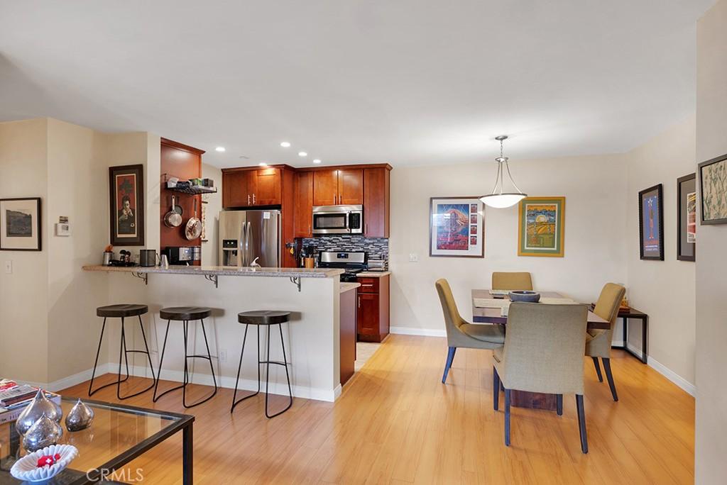 kitchen with kitchen peninsula, hanging light fixtures, appliances with stainless steel finishes, decorative backsplash, and a breakfast bar area