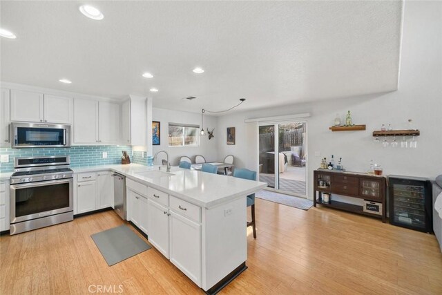 kitchen with white cabinets, stainless steel appliances, kitchen peninsula, and sink