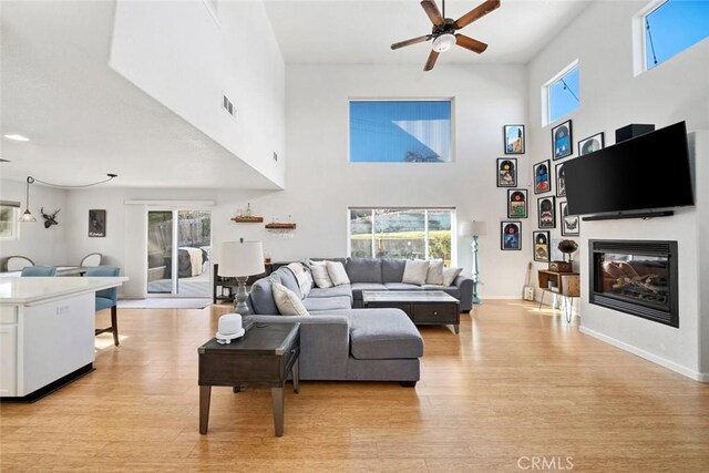 living room with light wood-type flooring, ceiling fan, and a wealth of natural light