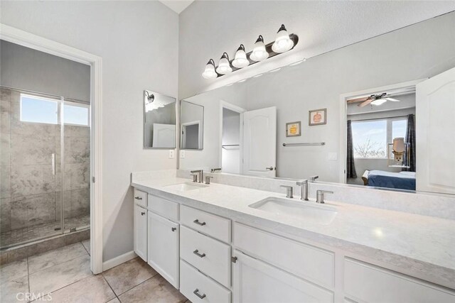 bathroom featuring a shower with shower door, a wealth of natural light, vanity, and tile patterned flooring