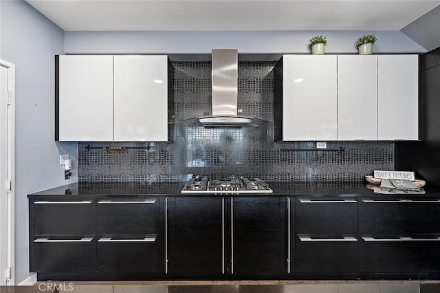 kitchen with wall chimney range hood, white cabinetry, decorative backsplash, and stainless steel gas cooktop