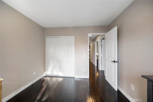 unfurnished bedroom featuring dark hardwood / wood-style floors and a closet