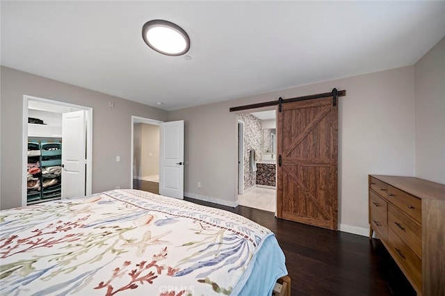 bedroom featuring a barn door, dark hardwood / wood-style flooring, and ensuite bath