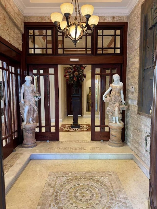 foyer entrance featuring a high ceiling, crown molding, an inviting chandelier, and french doors