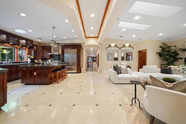 living room with decorative columns, crown molding, sink, and a skylight