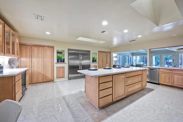 kitchen with stainless steel appliances, a center island, sink, and a skylight