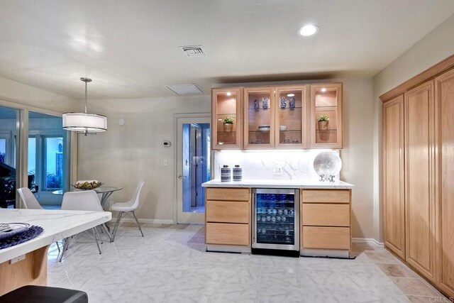 bar with wine cooler, decorative light fixtures, light brown cabinets, and backsplash