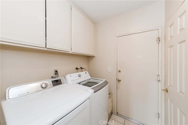 laundry area featuring separate washer and dryer, light tile patterned floors, and cabinets