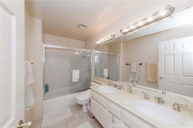 full bathroom featuring bath / shower combo with glass door, vanity, tile patterned floors, and toilet