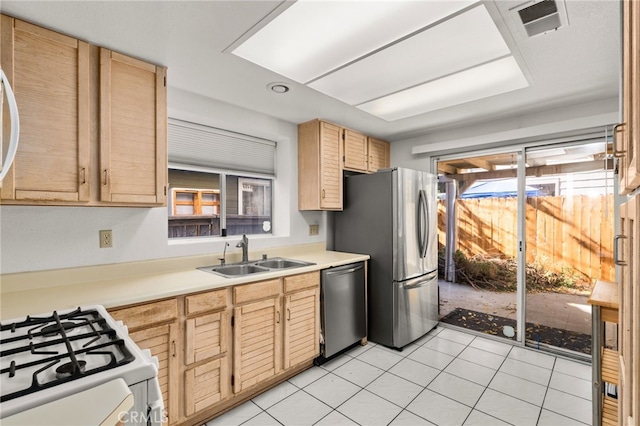 kitchen with light brown cabinetry, sink, light tile patterned floors, and stainless steel appliances