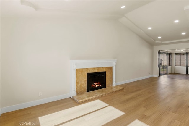 unfurnished living room featuring lofted ceiling, a fireplace, and wood-type flooring