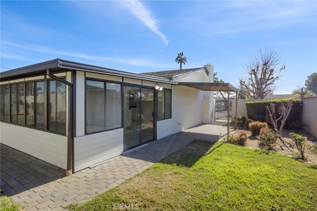 rear view of house featuring a yard and a sunroom