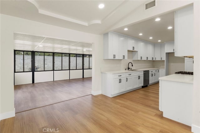 kitchen featuring sink, light hardwood / wood-style flooring, stainless steel gas stovetop, and white cabinets