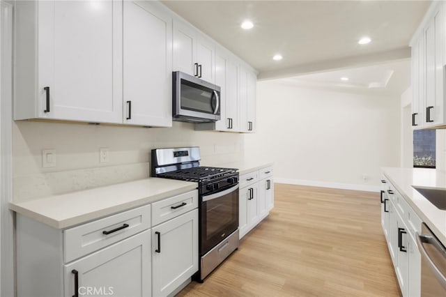 kitchen featuring stainless steel appliances, white cabinets, and light wood-type flooring