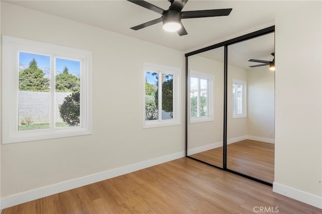 unfurnished bedroom with multiple windows, ceiling fan, a closet, and light wood-type flooring