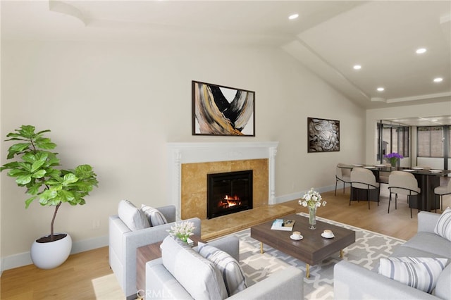 living room featuring lofted ceiling, a fireplace, and light hardwood / wood-style floors