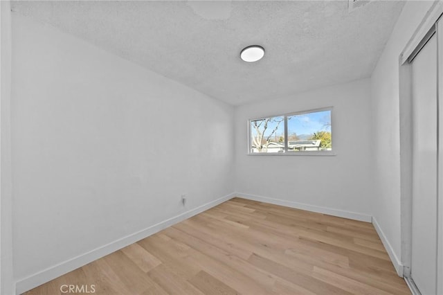 spare room featuring light hardwood / wood-style flooring and a textured ceiling